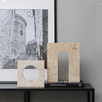 Decorative stone arches on a black shelf with a framed picture of a stone alleyway in the background.