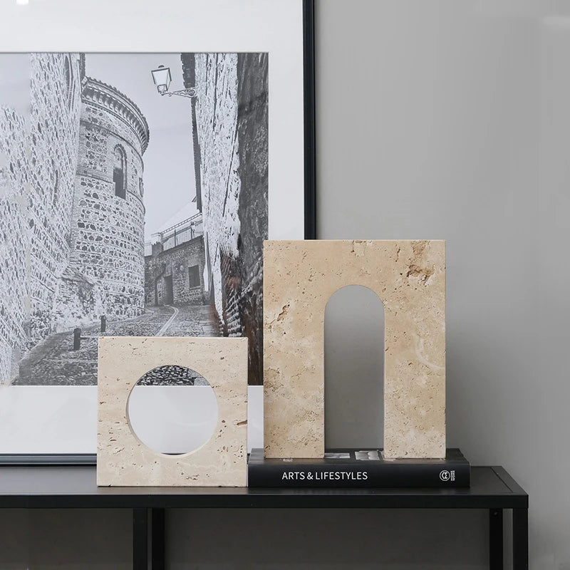 Decorative stone arches on a black shelf with a framed picture of a stone alleyway in the background.