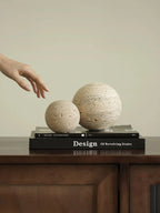 Two spherical objects on a book titled 'Design of Revolving Stairs' with a hand reaching towards them.