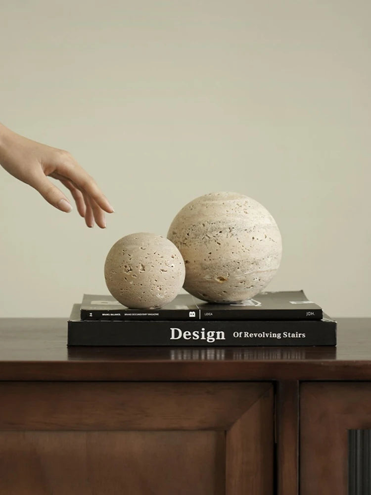 Two spherical objects on a book titled 'Design of Revolving Stairs' with a hand reaching towards them.