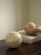 Two stone-like balls on a wooden surface with a blurred background