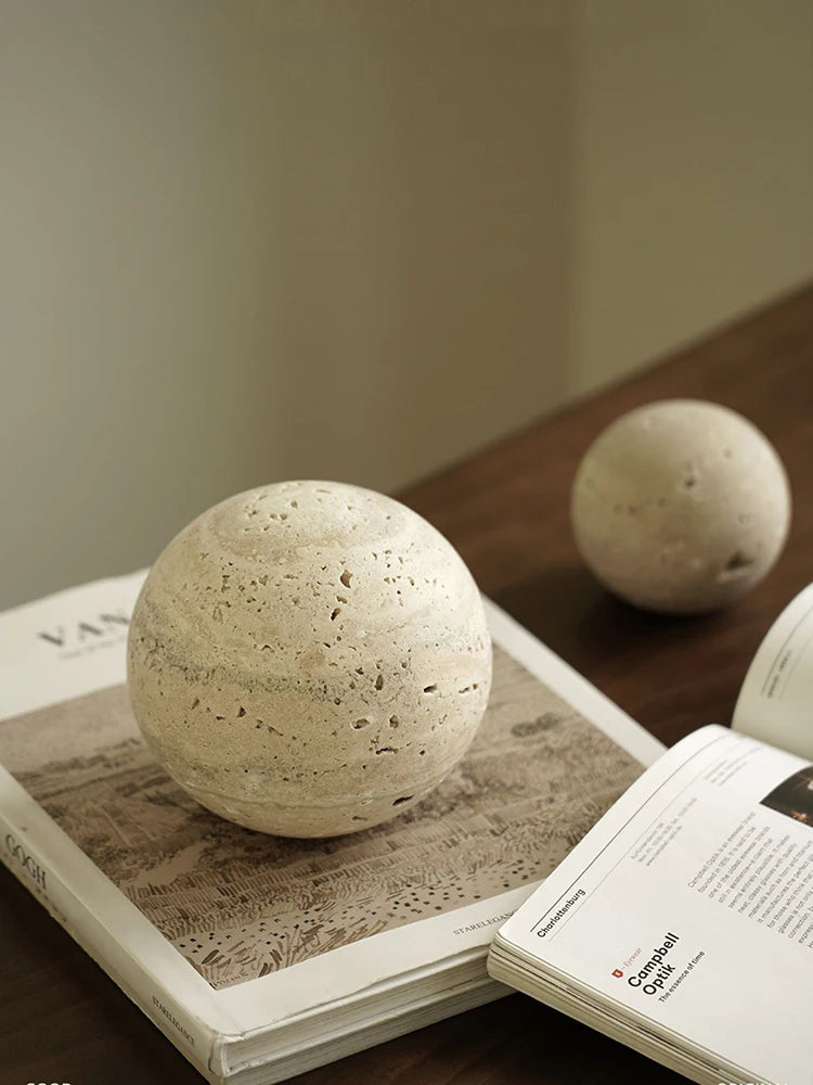 Decorative stone spheres on open books with a neutral background