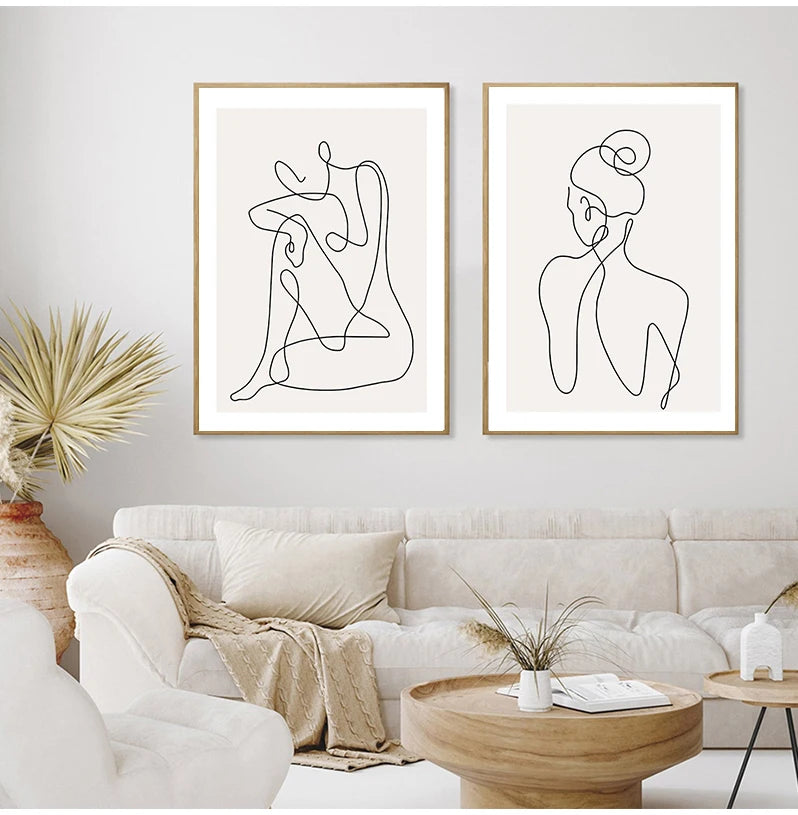 Two abstract line art prints on a wall above a sofa in a living room.