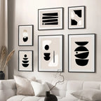 Modern wall art with abstract black and white designs on a neutral wall above a sofa.