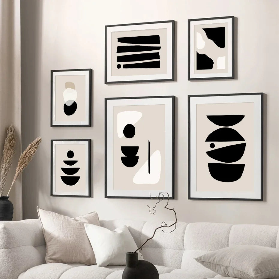 Modern wall art with abstract black and white designs on a neutral wall above a sofa.