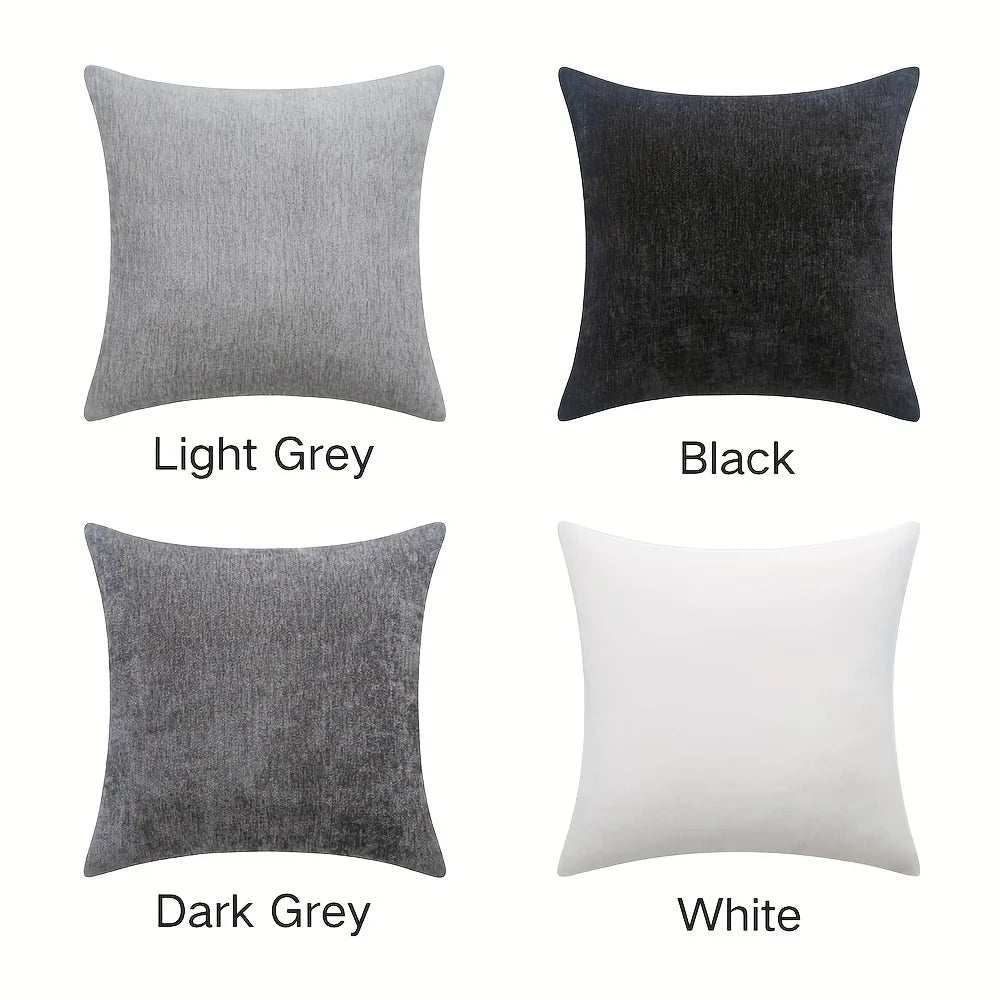 Four square pillows in light grey, black, dark grey, and white on a white background.