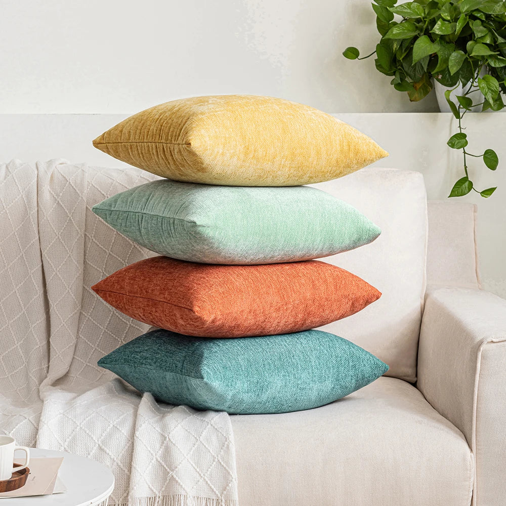 Stack of colorful pillows on a sofa with a plant in the background