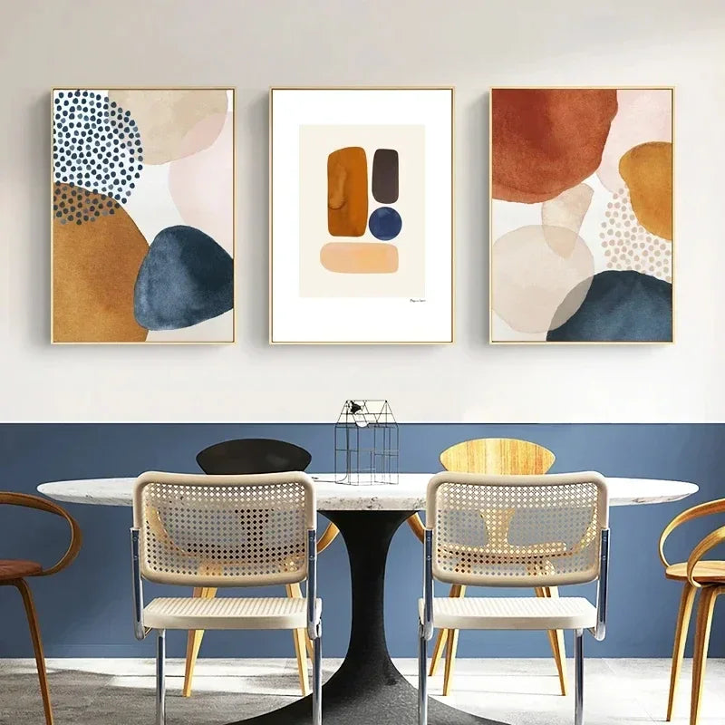 Abstract art prints on a wall above a dining table with chairs.