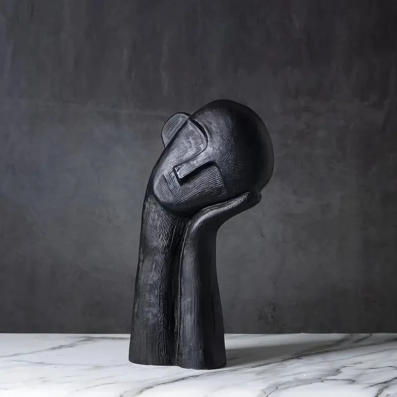 Black abstract sculpture on a marble surface with a dark gray background