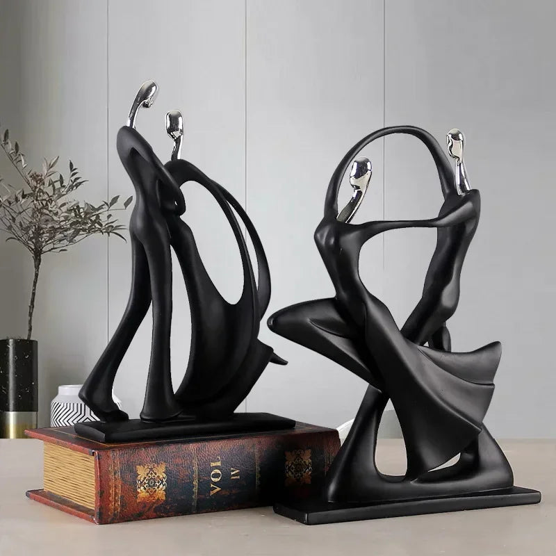 Two black abstract sculptures on a surface with a neutral background