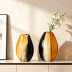 Two decorative vases with a floral arrangement on a shelf against a beige wall.