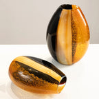 Two artistic glass vases with black and orange stripes on a white surface.
