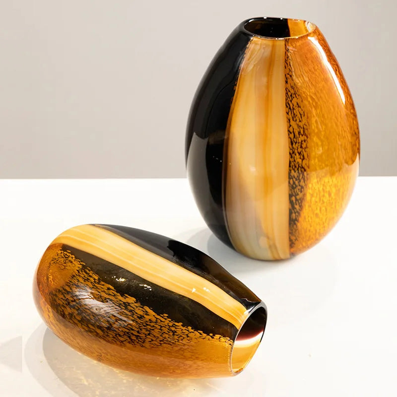 Two artistic glass vases with black and orange stripes on a white surface.