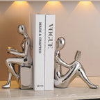 Silver abstract sculptures on a white platform with 'Vogue' book in the background