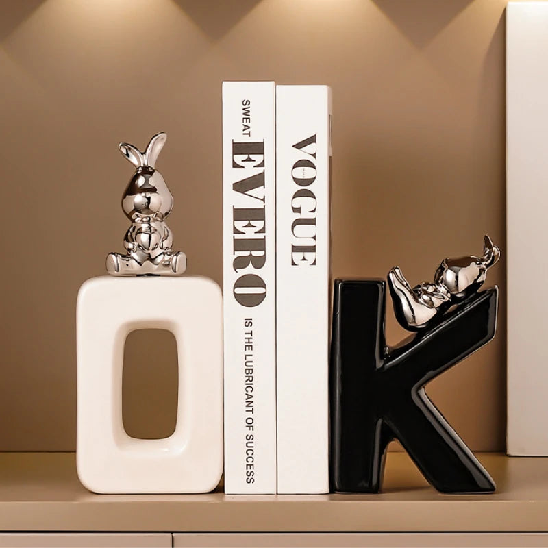 Decorative letters 'O' and 'K' with small figurines on top of books titled 'Vogue' and 'EVERO'.