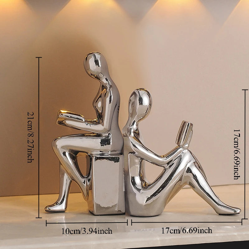 Silver abstract sculpture of two people on a beige background with measurements.