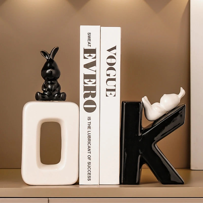 Decorative letter 'K' with a rabbit figure on top, next to a book titled 'Vogue', against a beige wall.