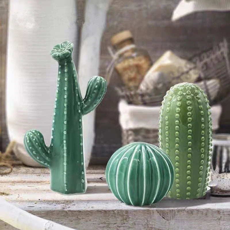 Three green ceramic cactus sculptures on a wooden surface with a blurred background.