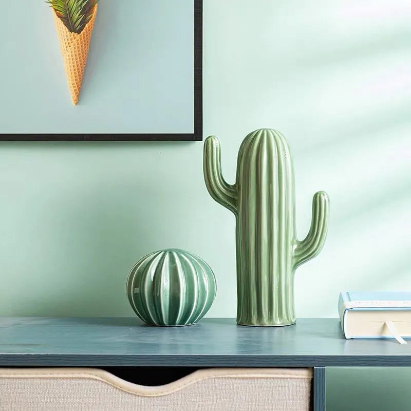 Two green cactus-shaped vases on a shelf with a light green wall in the background.