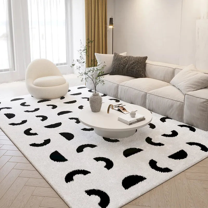 Modern living room with a white rug featuring black abstract patterns, a white sofa, and a round coffee table.