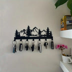 Key holder with mountain design on a wall with decorative items below.