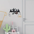 Decorative hook with mountain design on a wall above a shelf with a guitar and cactus decoration.