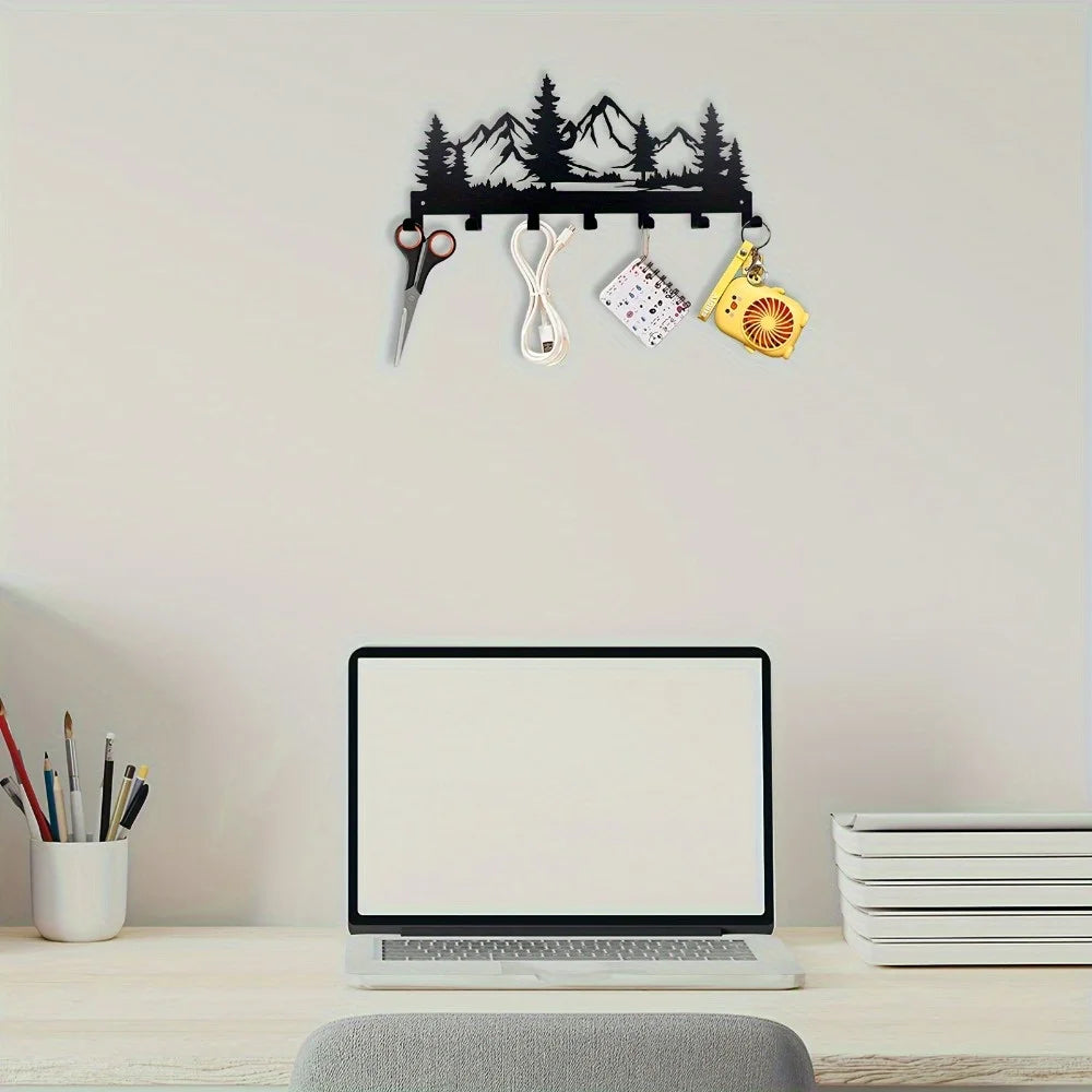 Wall-mounted key holder with nature design above a desk with laptop and stationery.