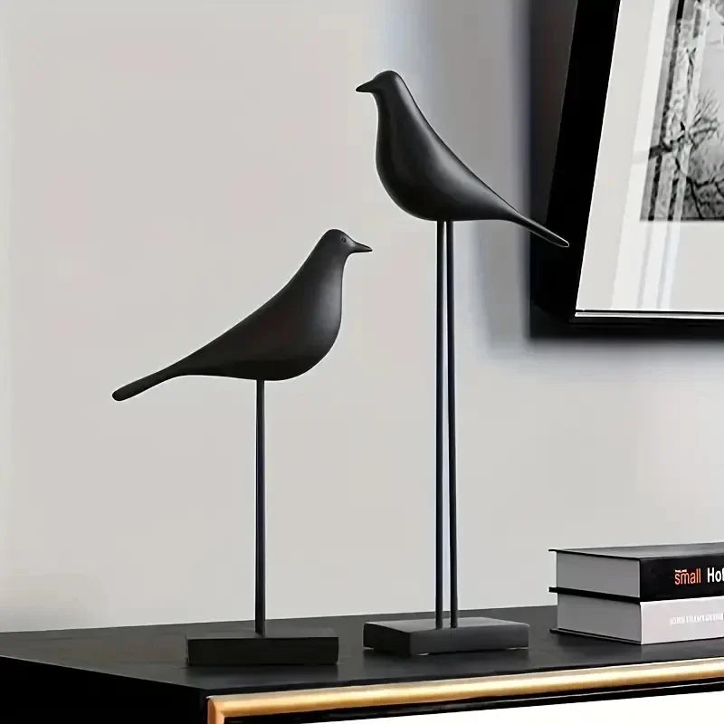 Two black bird sculptures on a shelf with a neutral background