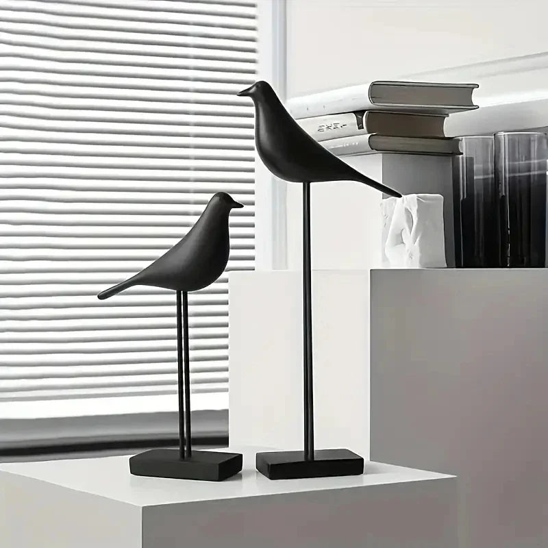Two black bird-shaped lamps on a white surface with a blurred background