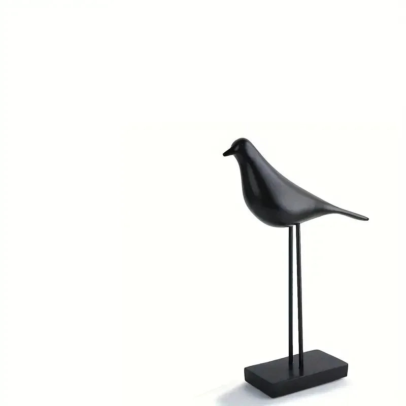 Black bird-shaped sculpture on a stand against a white background