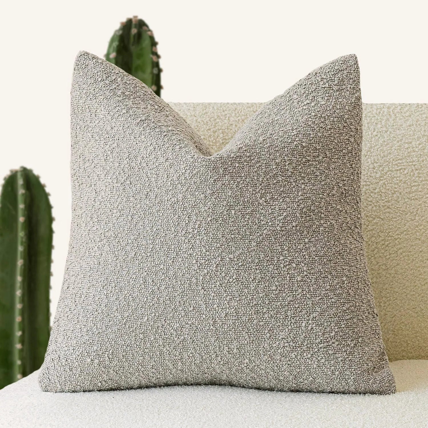 Textured gray pillow on a light-colored sofa with cacti in the background