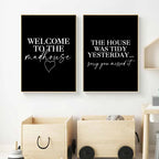Two black posters with humorous text on a white wall above wooden storage boxes.
