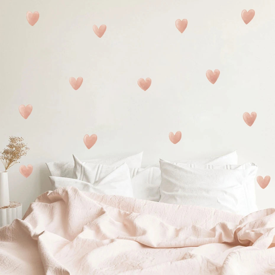 Bed with pink bedding and heart-shaped wall decals on a light background