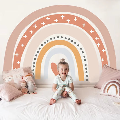 Child sitting on a bed with a colorful rainbow wall mural in the background