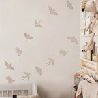 Children's room with wall decals of birds and a shelf with toys and books.