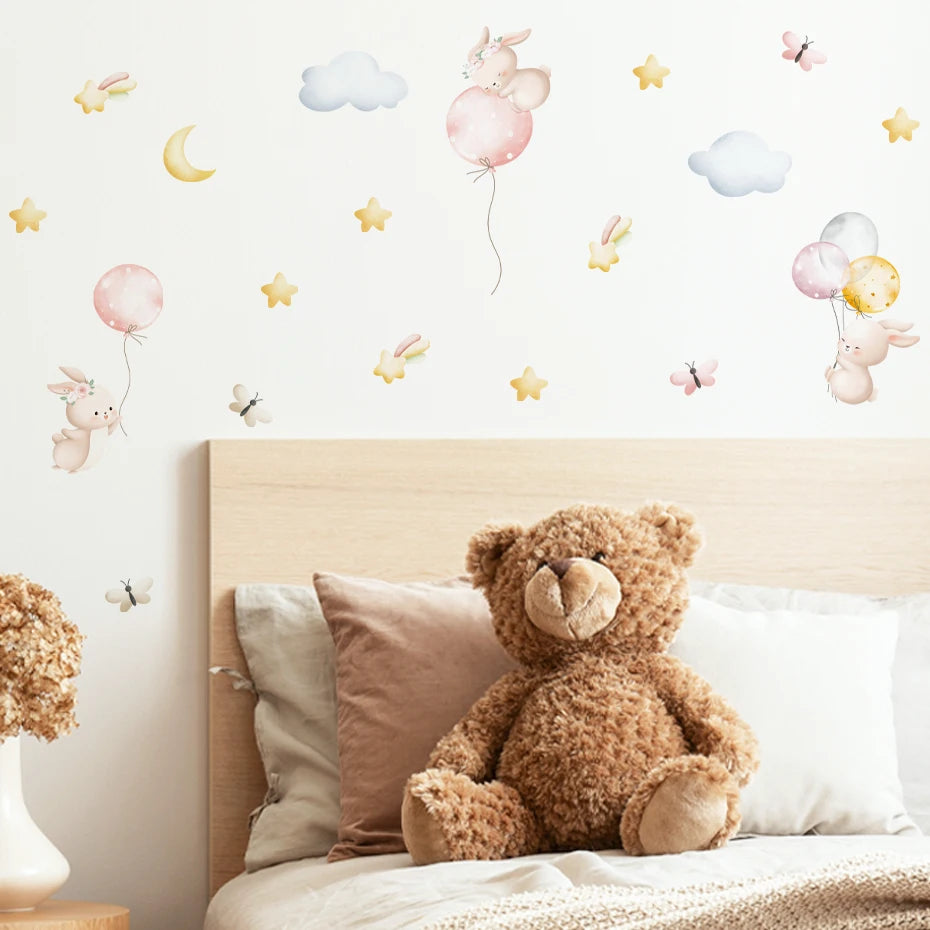 Teddy bear on a bed with decorative wall stickers of balloons and animals in a child's bedroom.