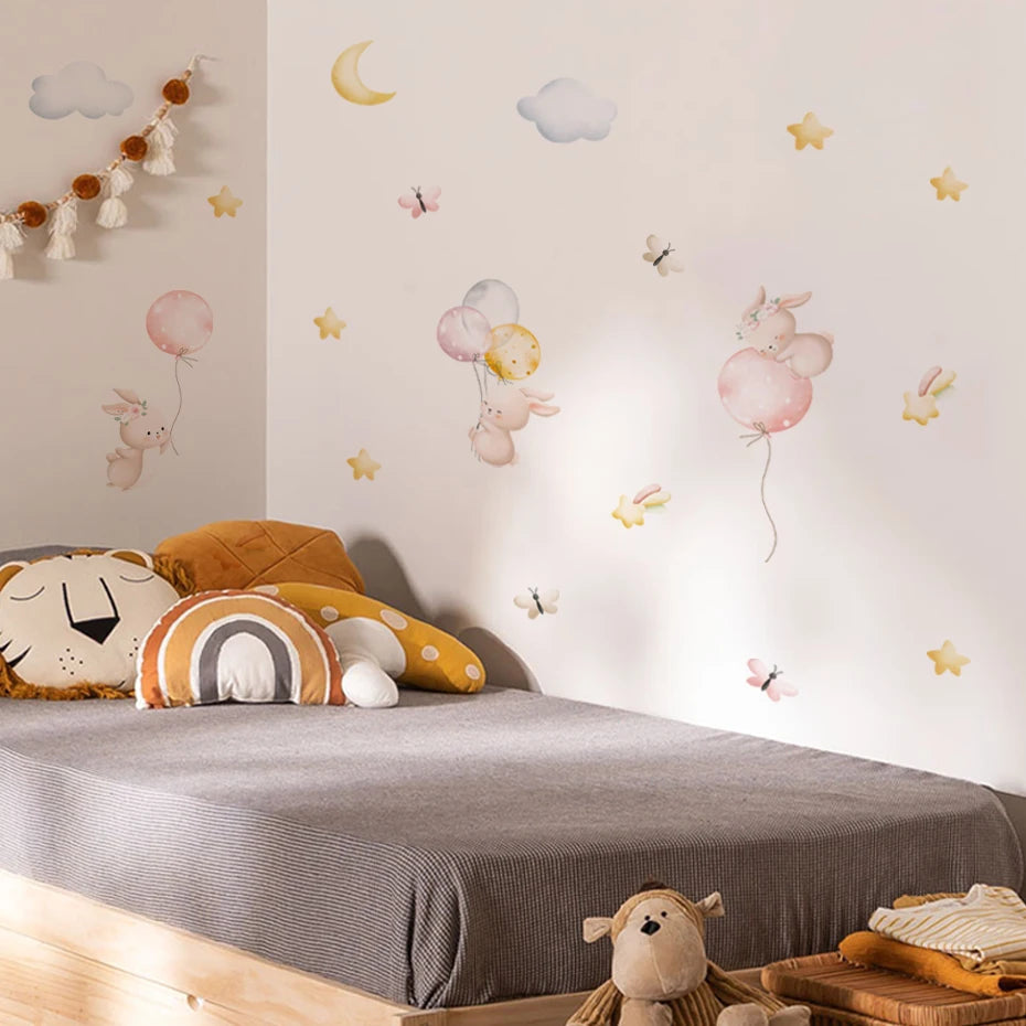 Children's room with decorative wall stickers, pillows, and a teddy bear.