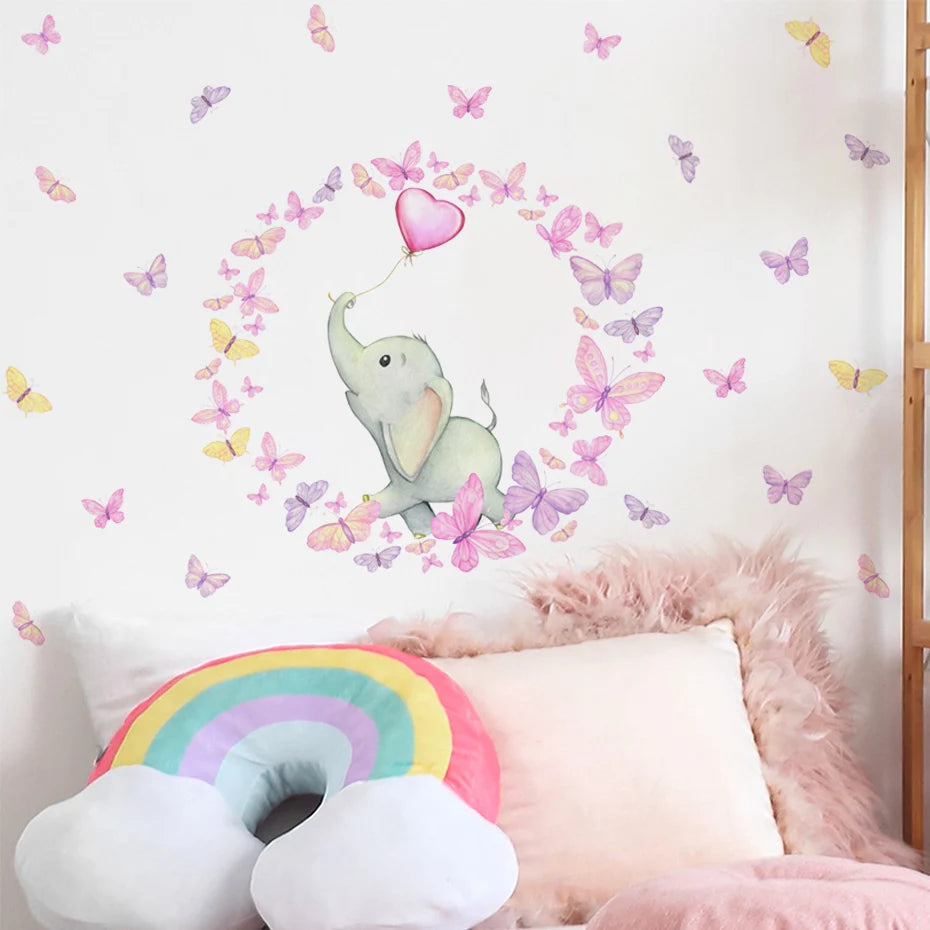 Wall decal of an elephant surrounded by butterflies and a heart, with pillows and a rainbow decoration below.