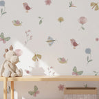 Children's room with wallpaper featuring birds, flowers, and butterflies, and a wooden shelf with a plush toy.
