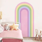 Children's bedroom with a rainbow mural on the wall, pink bedding, and colorful pillows.