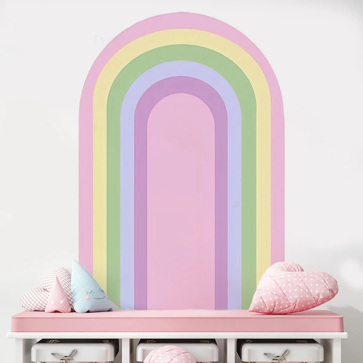 Pastel rainbow wall decal on a white wall with pink shelf and decorative items.