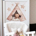 Wall decal of a teddy bear in a teepee with stars on a white wall above a chair.