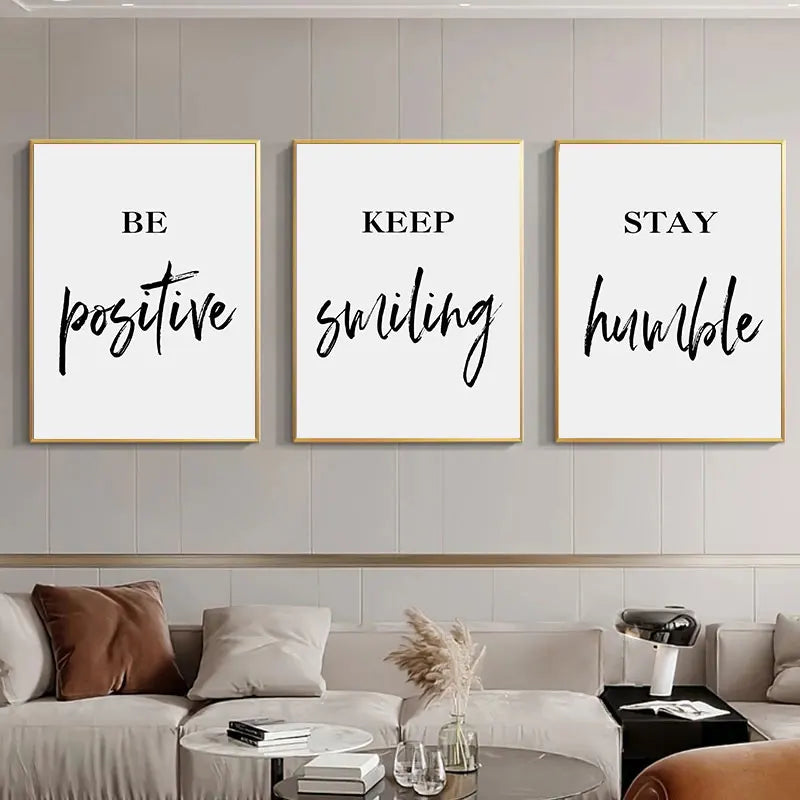 Three motivational posters with inspirational quotes on a wall above a sofa.
