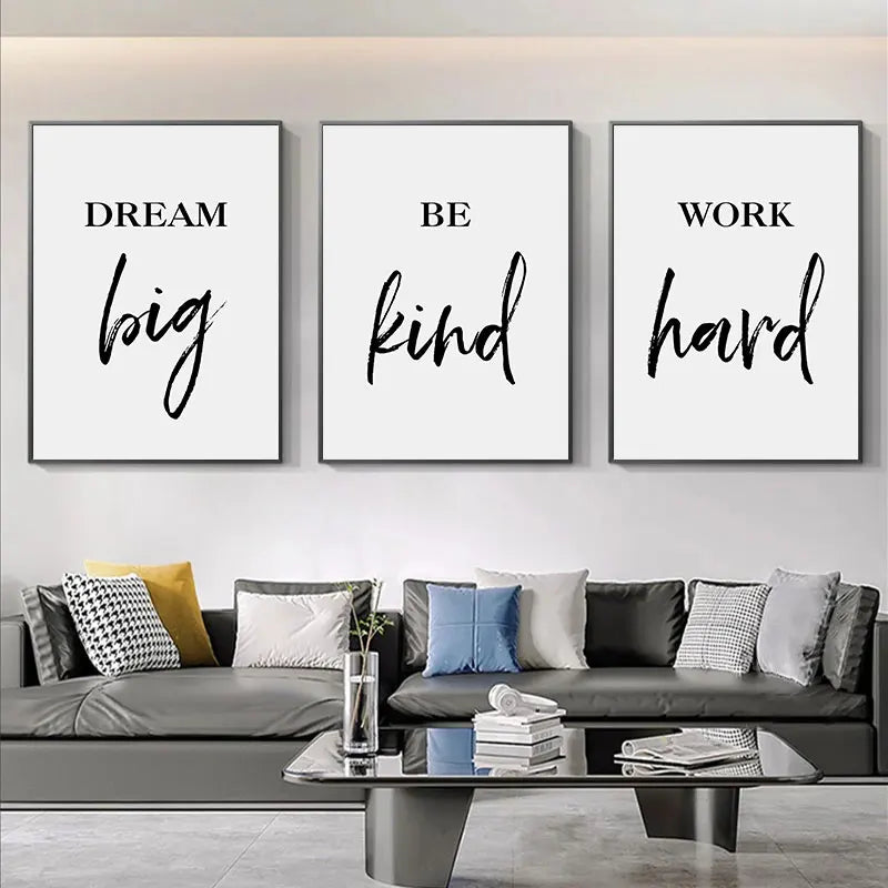 Three motivational posters on a wall above a sofa with decorative pillows.