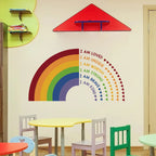 Children's playroom with a rainbow wall decal and motivational phrases.