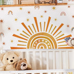 Crib with teddy bears and a decorative wall mural of a sun and rainbow in a nursery.