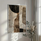 Abstract art piece on a wall with a vase of dried plants in the foreground.