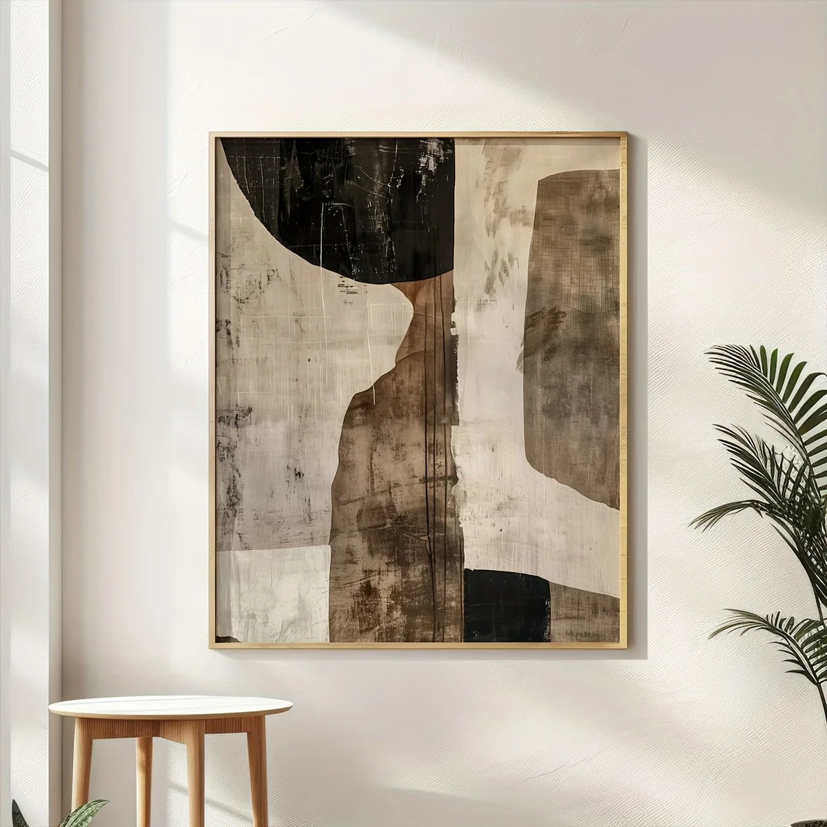 Abstract art piece in a gold frame on a wall with a plant and small table.