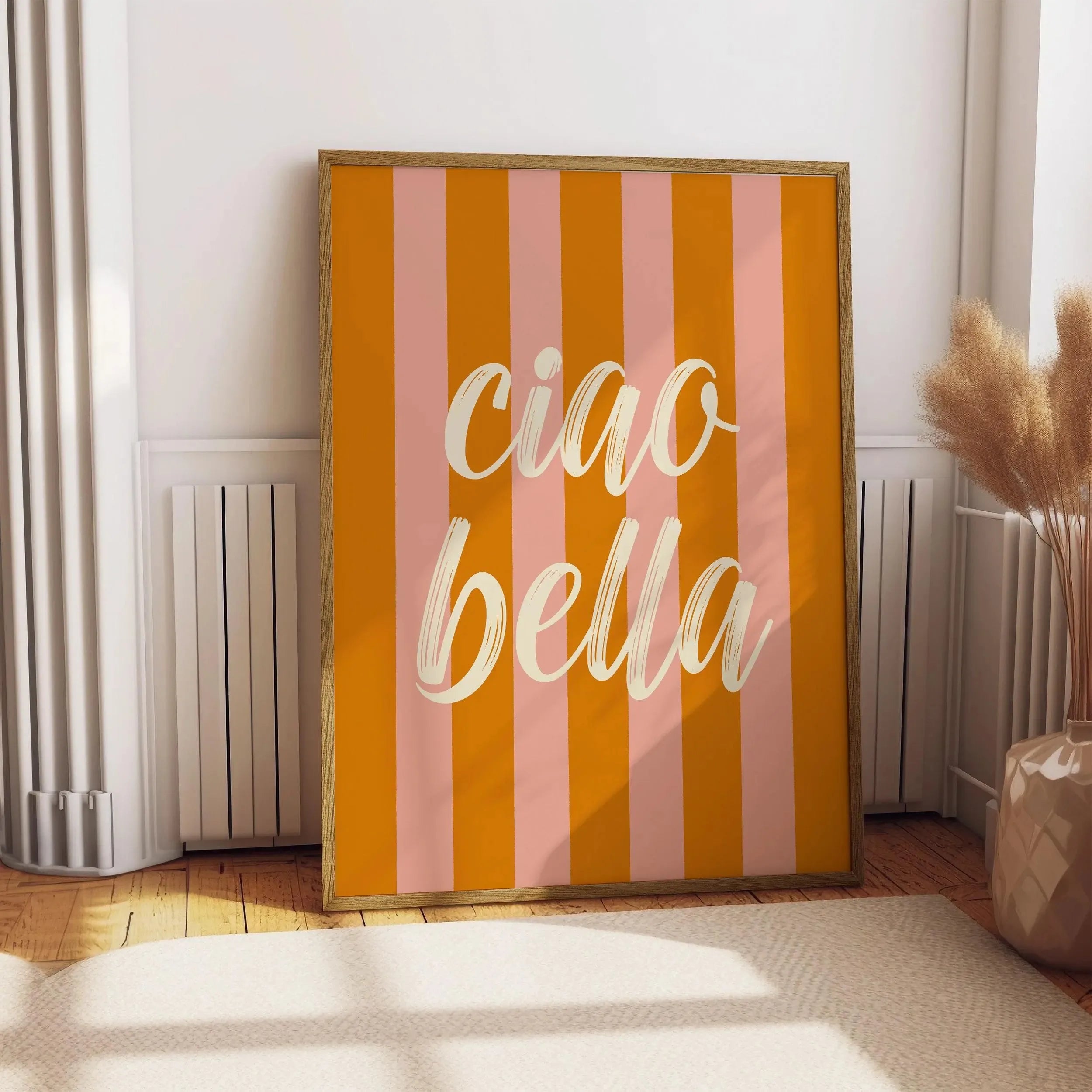 Framed artwork with 'ciao bella' on a striped background in a room.