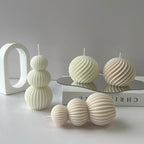 Set of textured spherical candles on a reflective surface with a minimal background